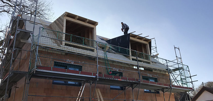 Handwerker von E&G Bedachungen steht auch Dachgaube und deckt Dach